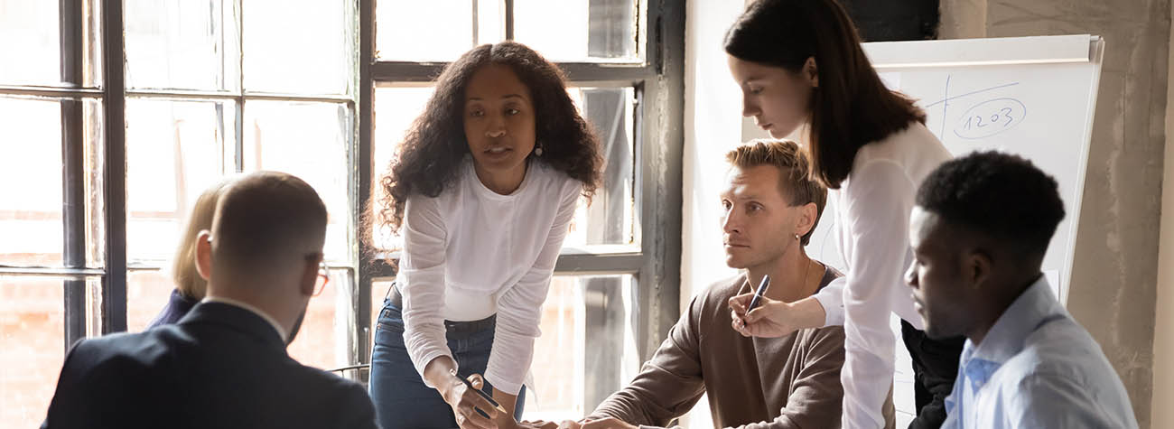 A diverse group of business professionals, male and female, collaborating energetically in an office setting