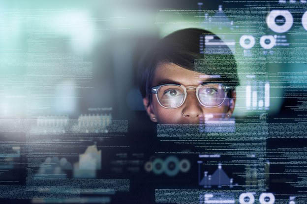 Young male programmer with computer screen reflected in his glasses, showing various code and data outputs