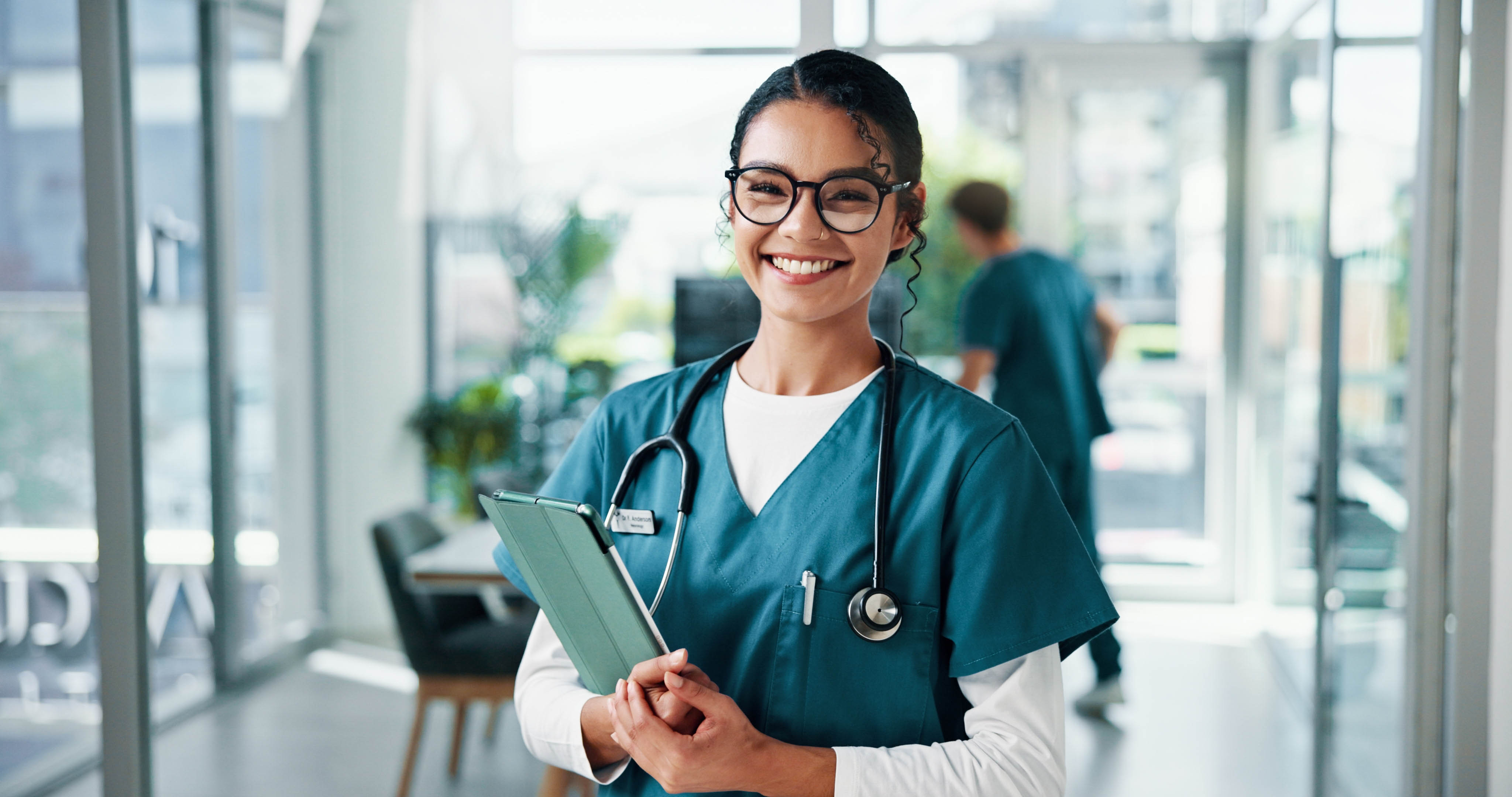 Smiling nursing student in uniform holding a tablet and stethoscope, representing the Licensed Practical Nursing profession in Chicago