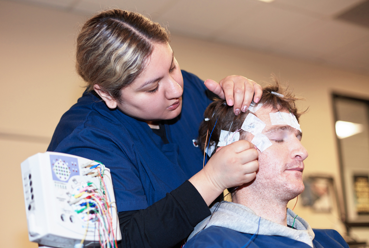 MCC student securing electrodes on a test subject for long-term EEG recording and epilepsy monitoring in the lab